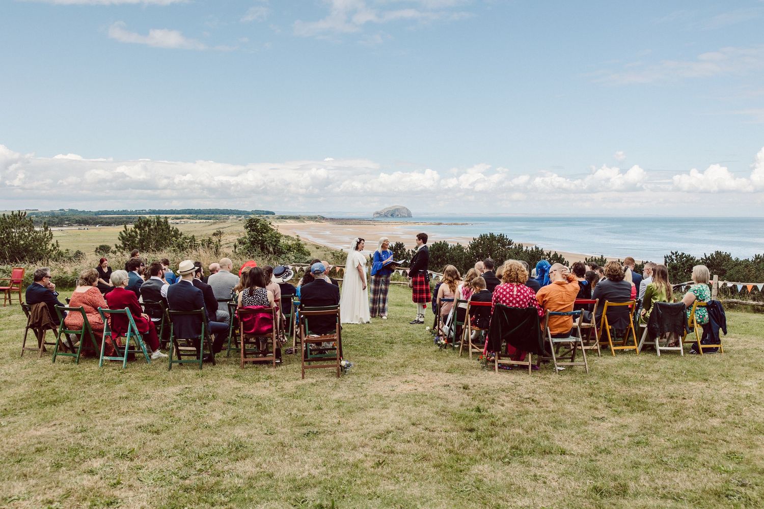 Wedding guests line up outside to create a tunnel for the newlyweds to walk through during an outdoor celebration.