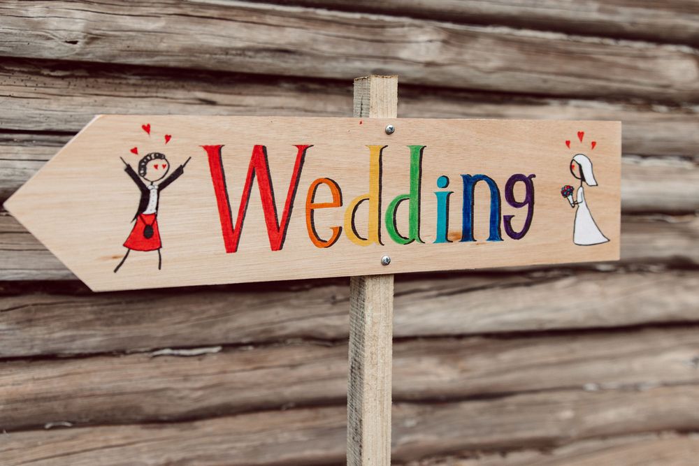 Rustic wooden wedding signs with decorative text mounted on weathered log walls.
