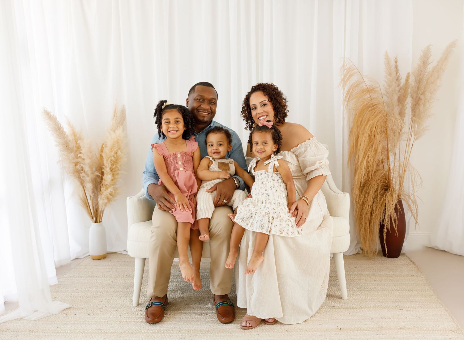 Family portrait session in bright white studio with natural pampas grass decor.
