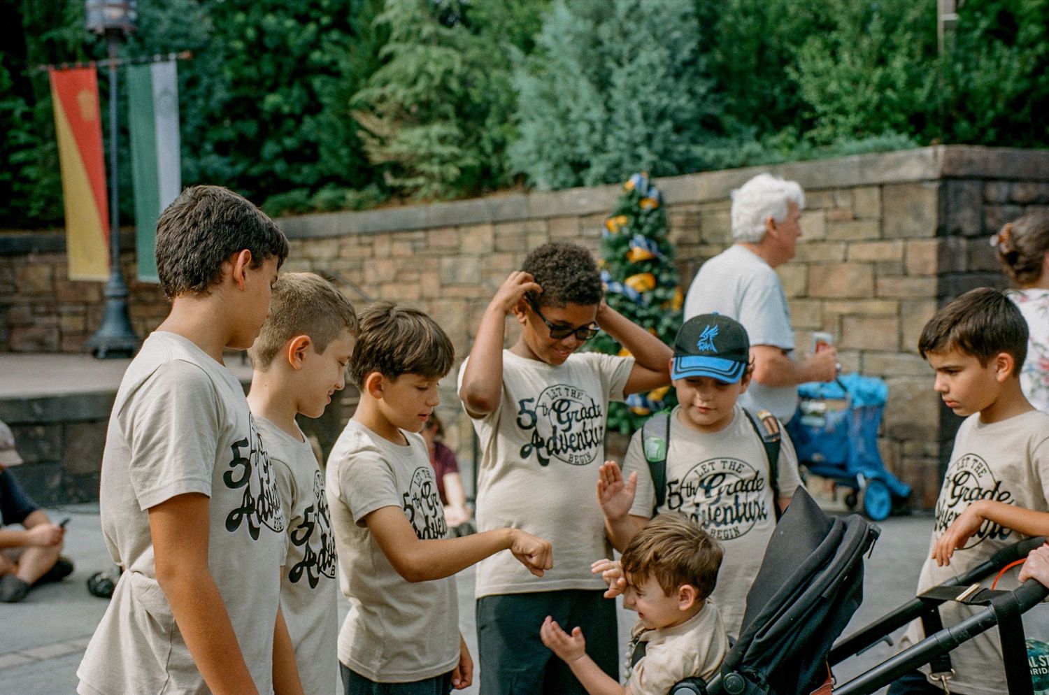 A group of people wearing matching t-shirts gather around to look at something together in an outdoor setting.