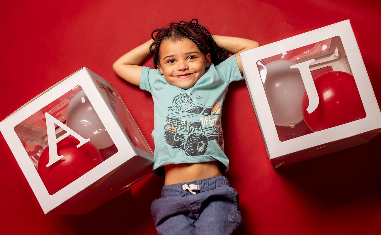 Child lying on red background with decorative white letter boxes.