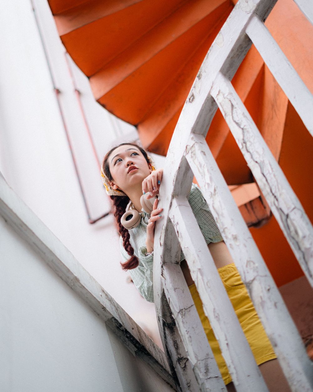 Low angle view of orange spiral staircase and white walls creating geometric composition.