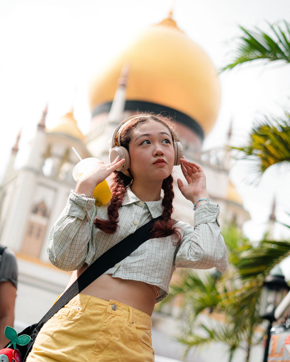 Fashion portrait with golden dome mosque and palm trees in background.