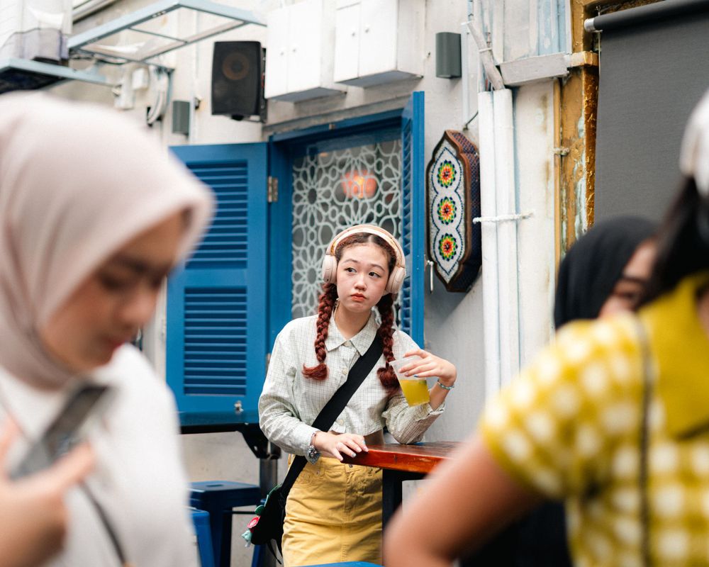 Street photography capturing casual fashion among urban crowd and blue storefront.