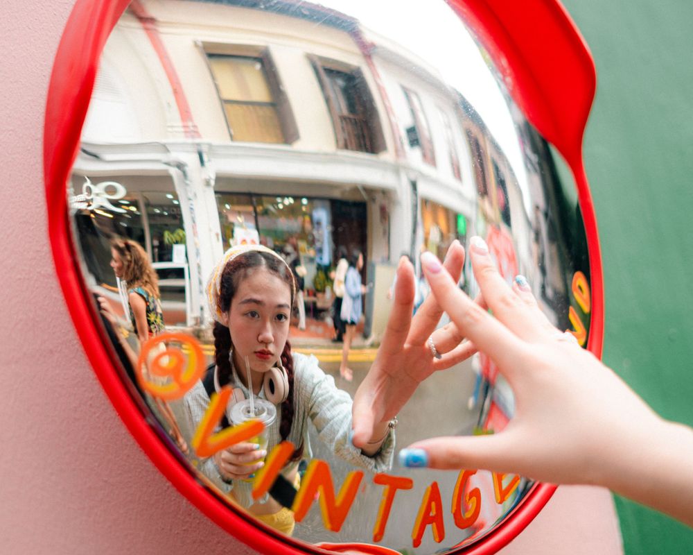 A whimsical reflection in a convex safety mirror with a hand reaching out.