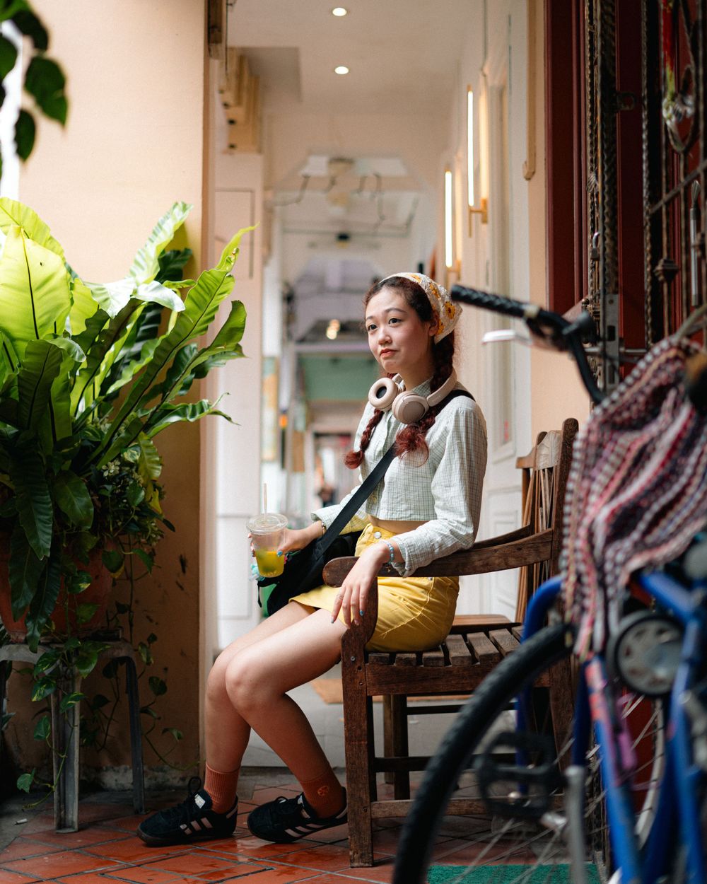 A casual indoor portrait with potted plants and natural lighting in a cozy cafe setting.