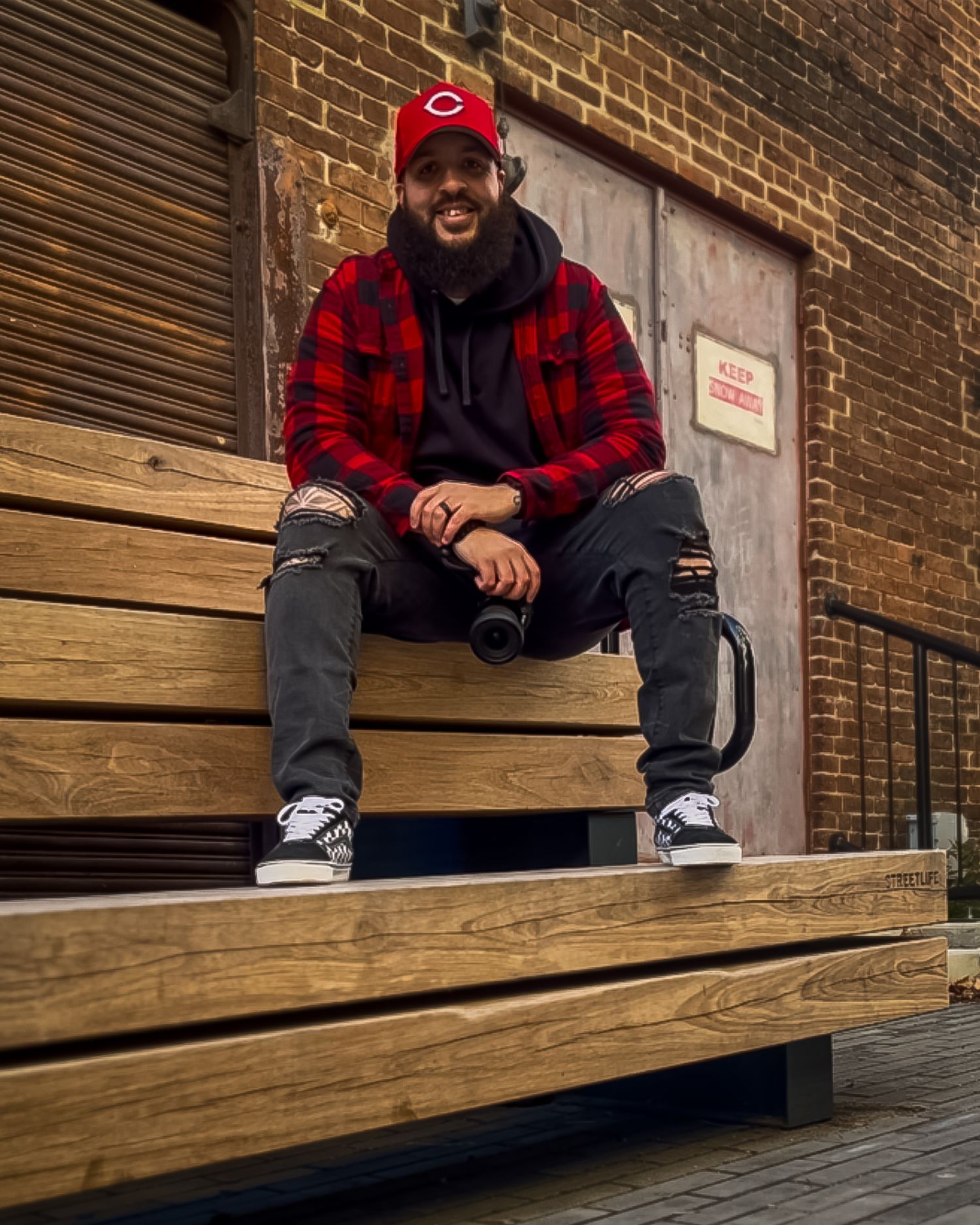 Wooden benches or bleachers against a brick wall in an urban setting.