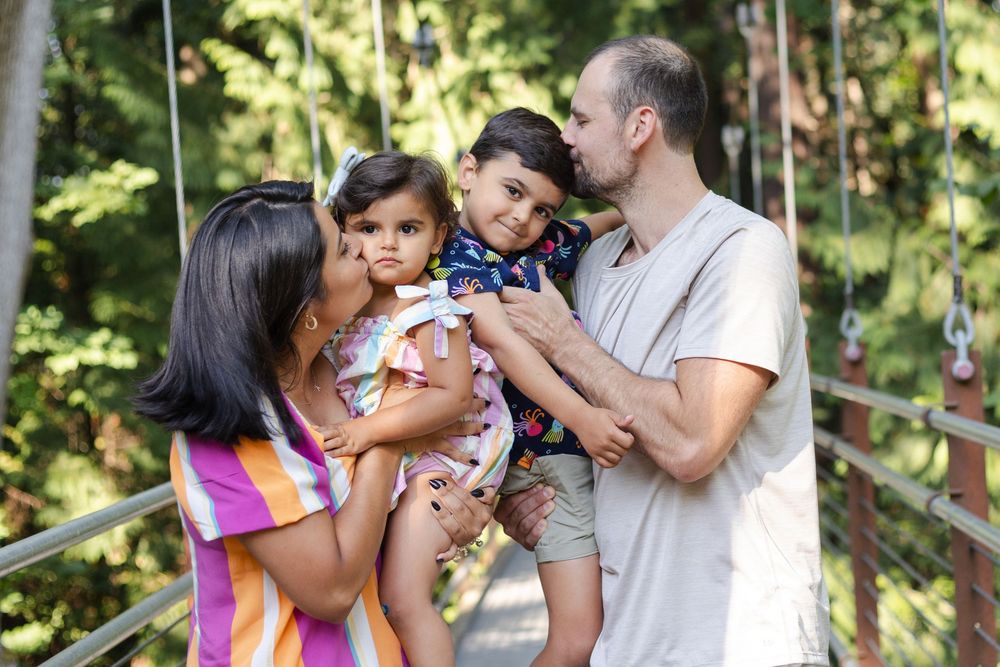 Family members embrace and share joyful moments together in a sunny outdoor setting.