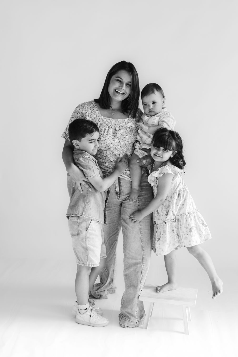 A series of black and white family portraits showing tender moments between a parent and children in matching outfits.