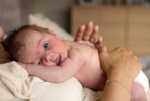 Newborn baby lying on soft blanket during bath time with tiny hand raised.