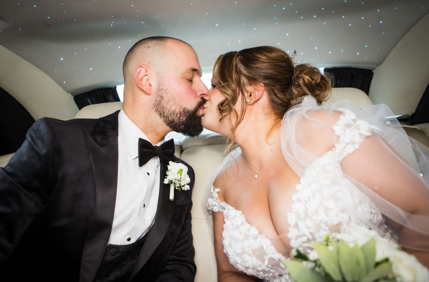 Romantic moment shared between newlyweds in car after wedding ceremony.
