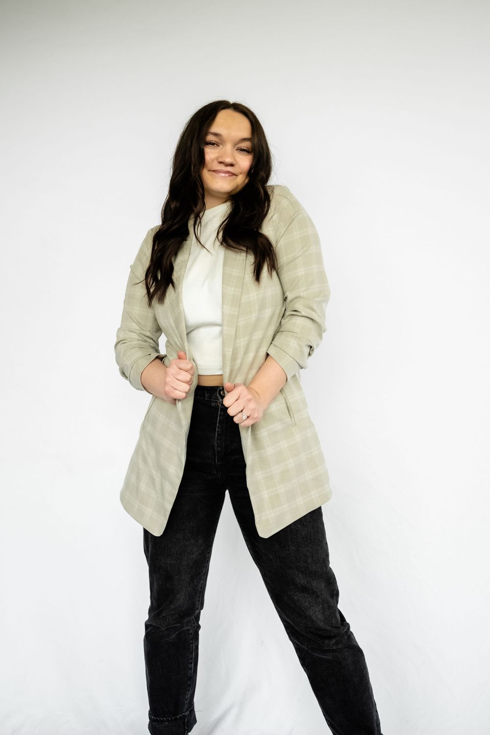 Studio fashion shot featuring quilted beige jacket and black jeans against white background.