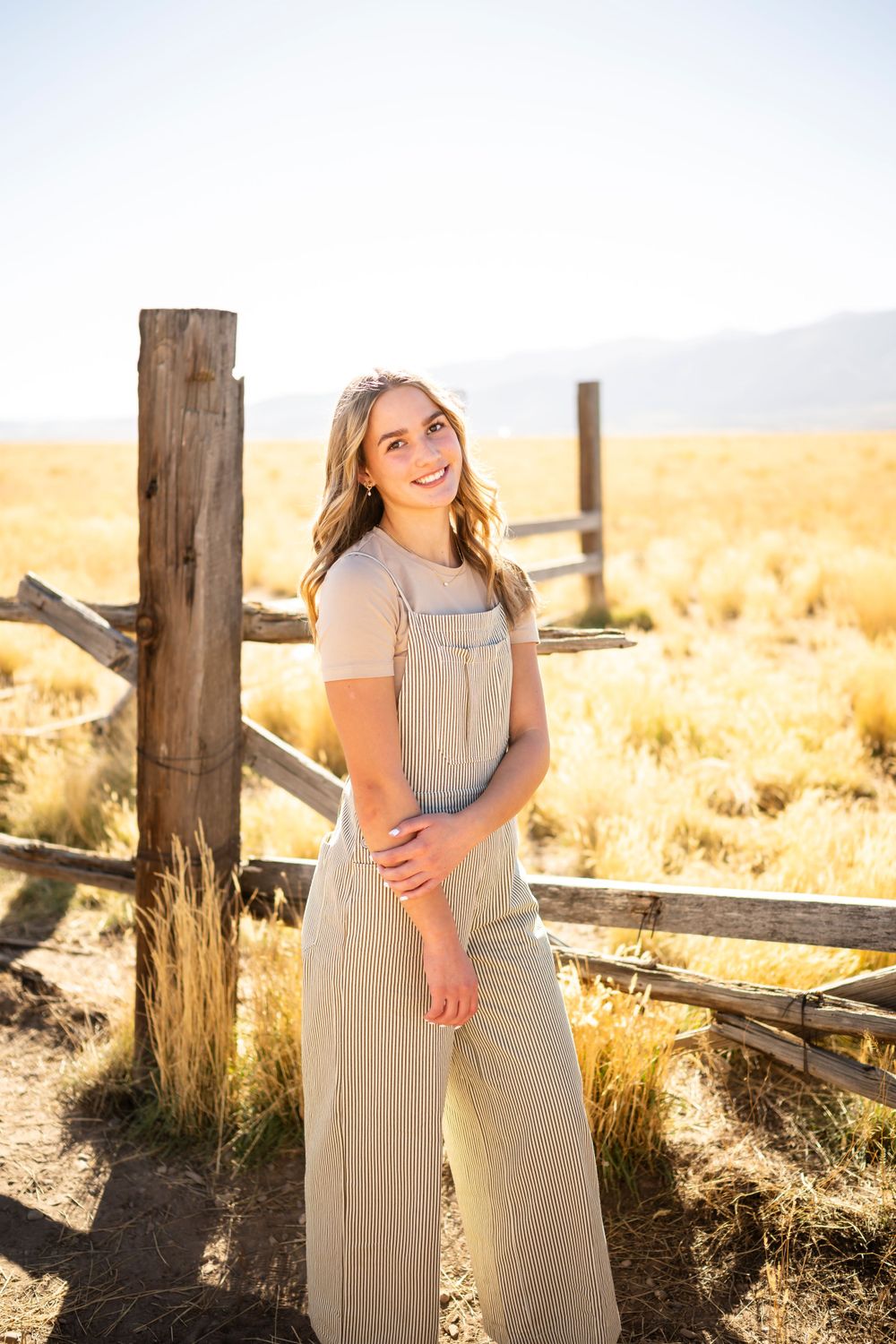 Portrait session at golden hour by a wooden fence in a desert landscape.