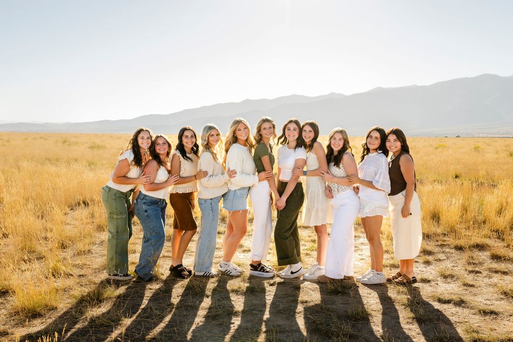 Group photo of people wearing coordinated outfits standing in line during sunset in desert setting.