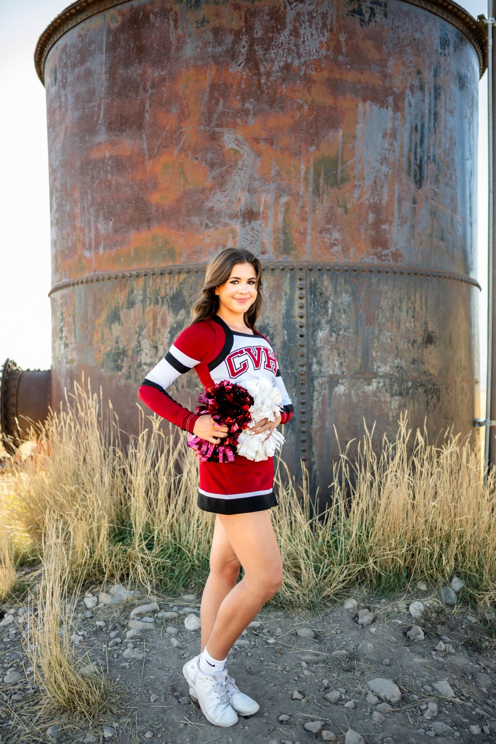Portrait session against rustic metal tanks with tall grass in the background.