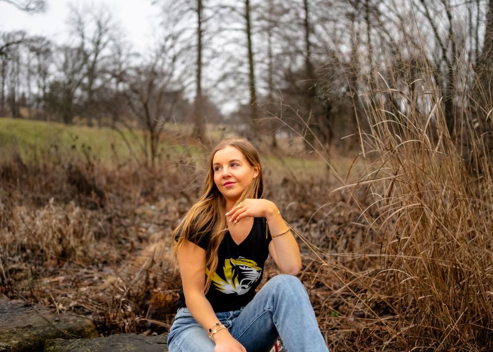 Outdoor portrait session in a natural setting with dried grass and trees.