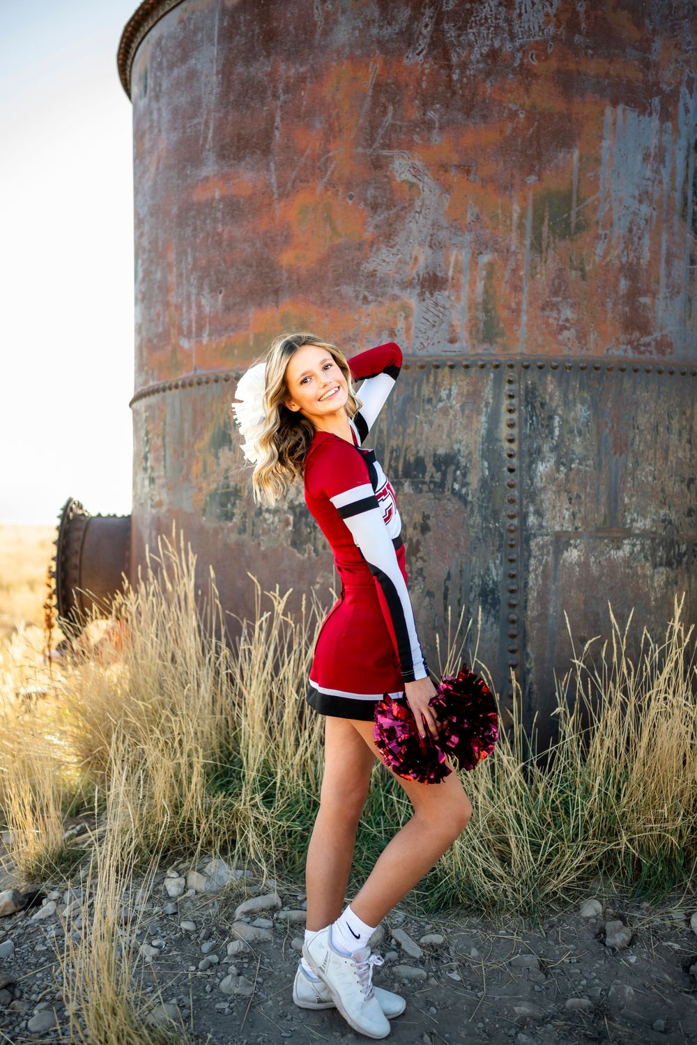 Cheerleader in red uniform performs dynamic poses against industrial metal background.