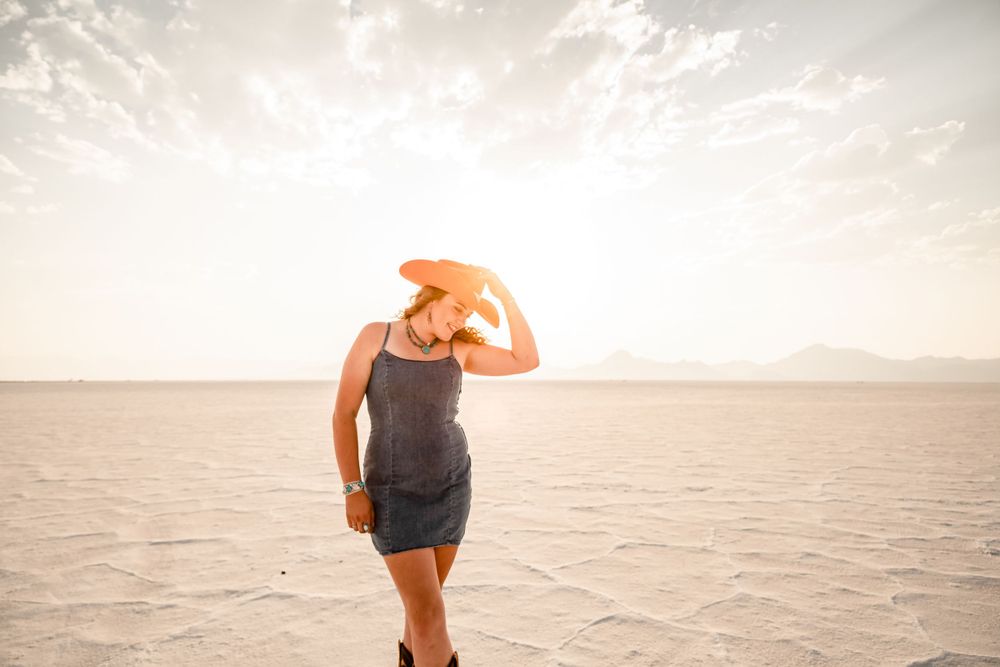Silhouette in hat walking across desert landscape at sunset.