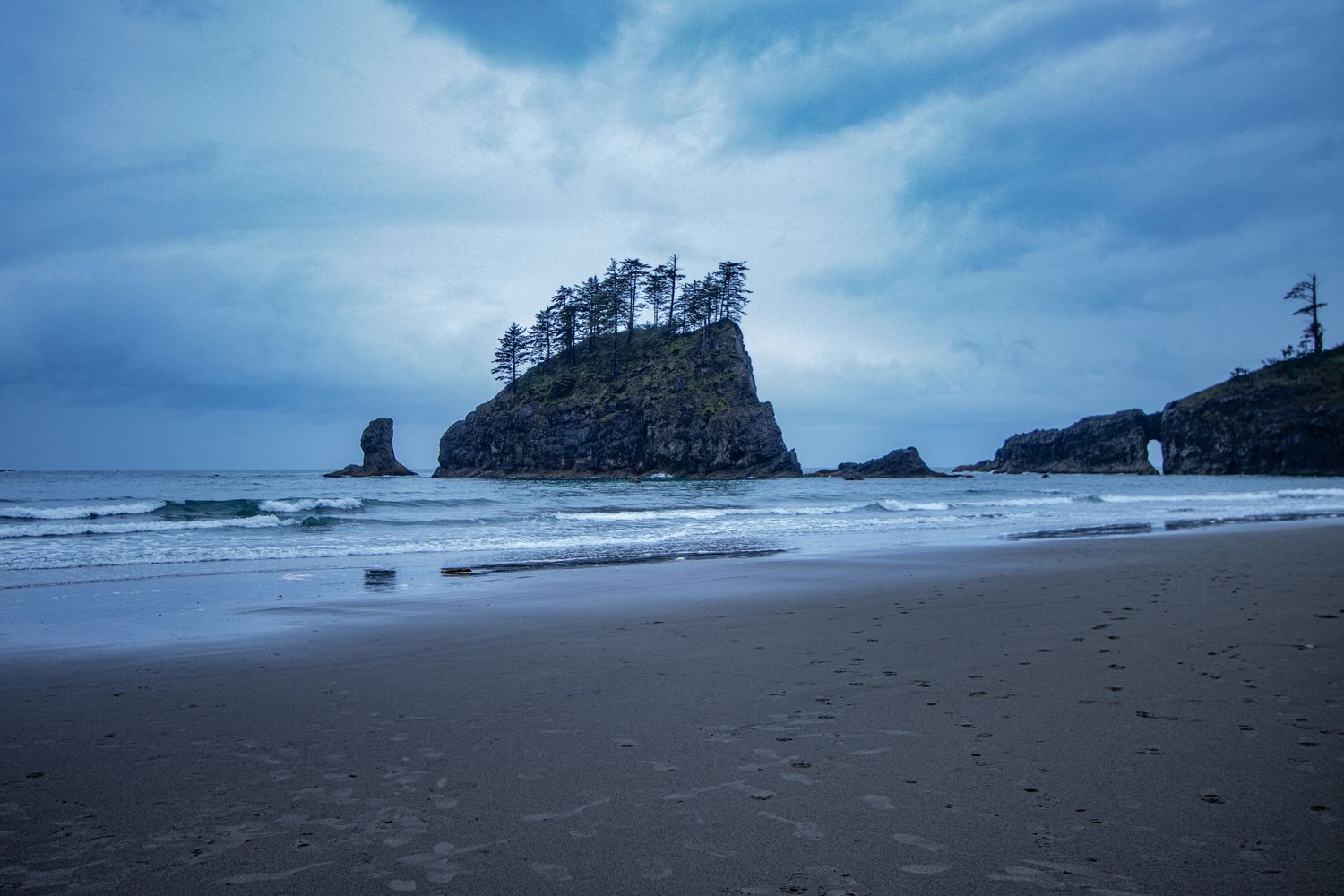 Coastal landscape on a cloudy day with offshore seastacks and islands.