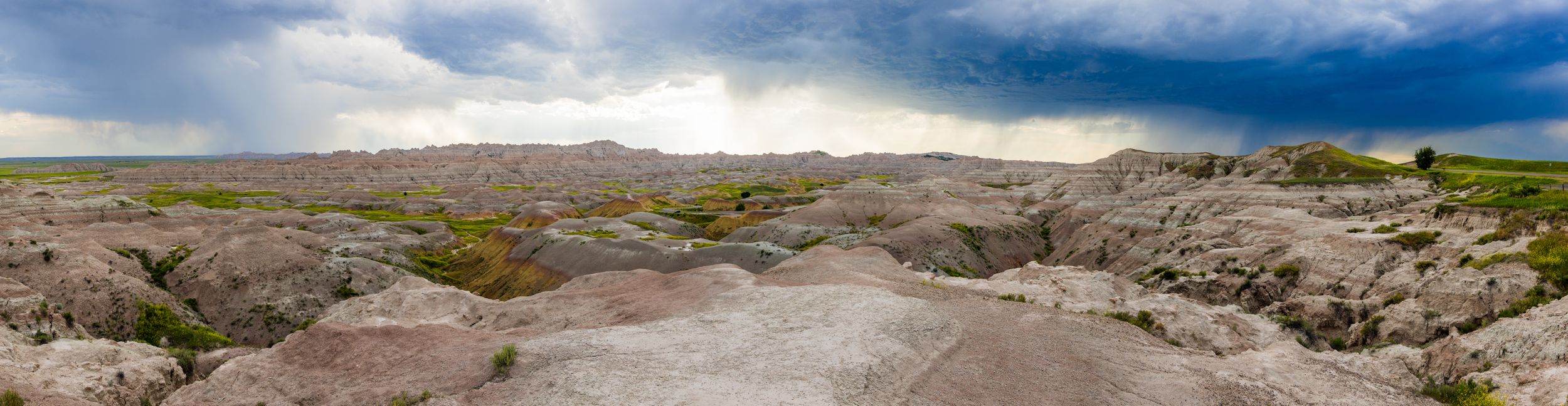 Dramatic panoramic view of cloudy skies over a rugged desert landscape.