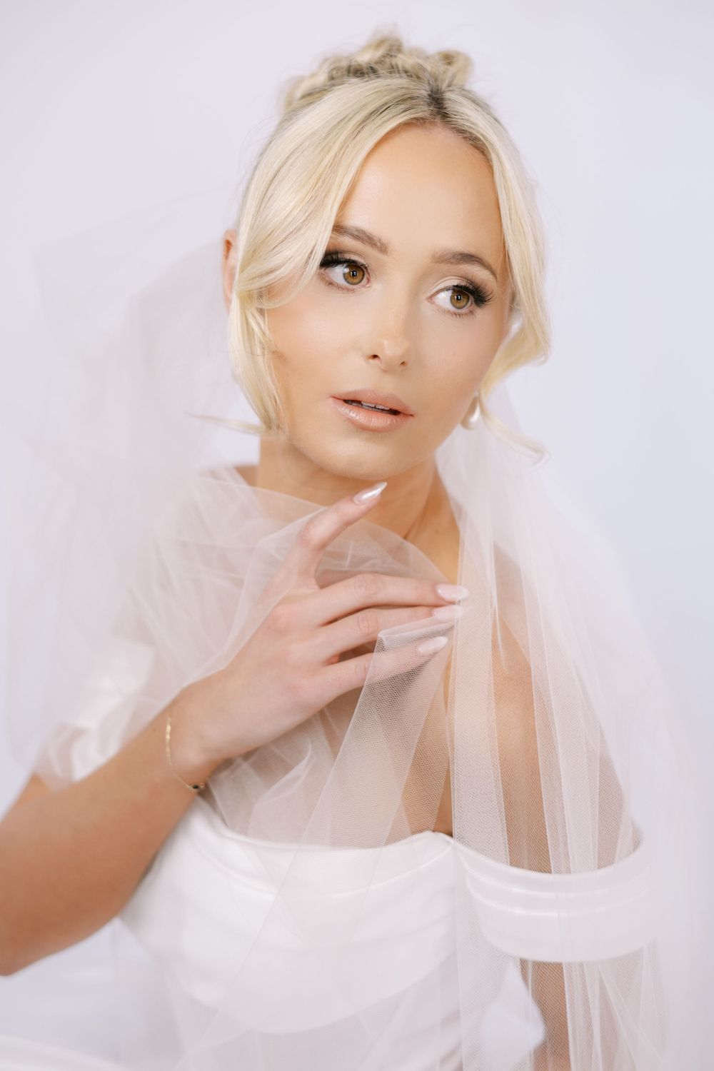 Intimate bridal portraits with sheer veil and classic makeup in soft lighting.