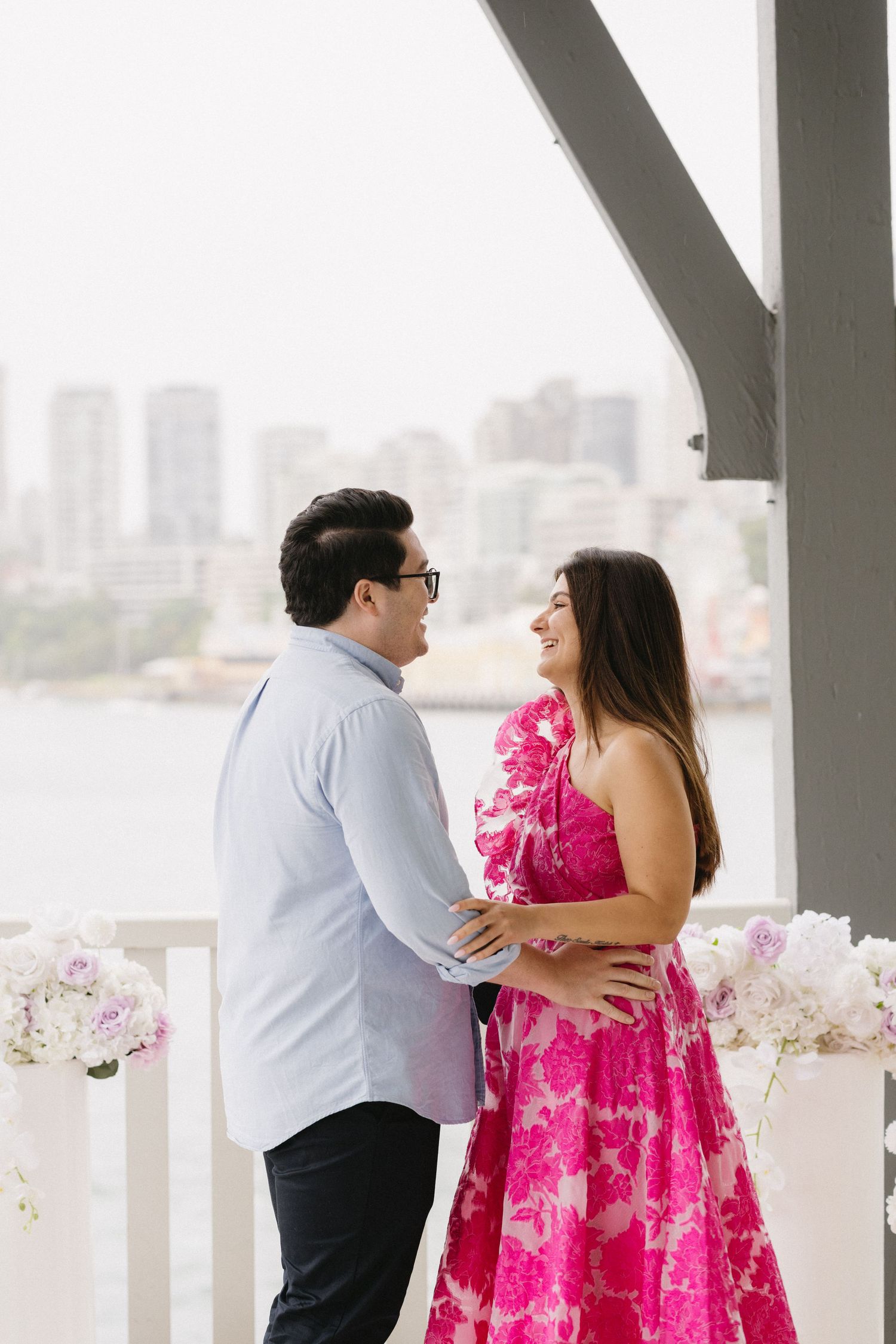 A couple sharing a romantic moment on a waterfront balcony.