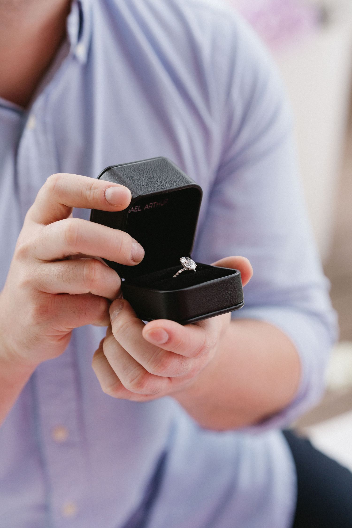 Hands holding a black engagement ring box in anticipation of a proposal.
