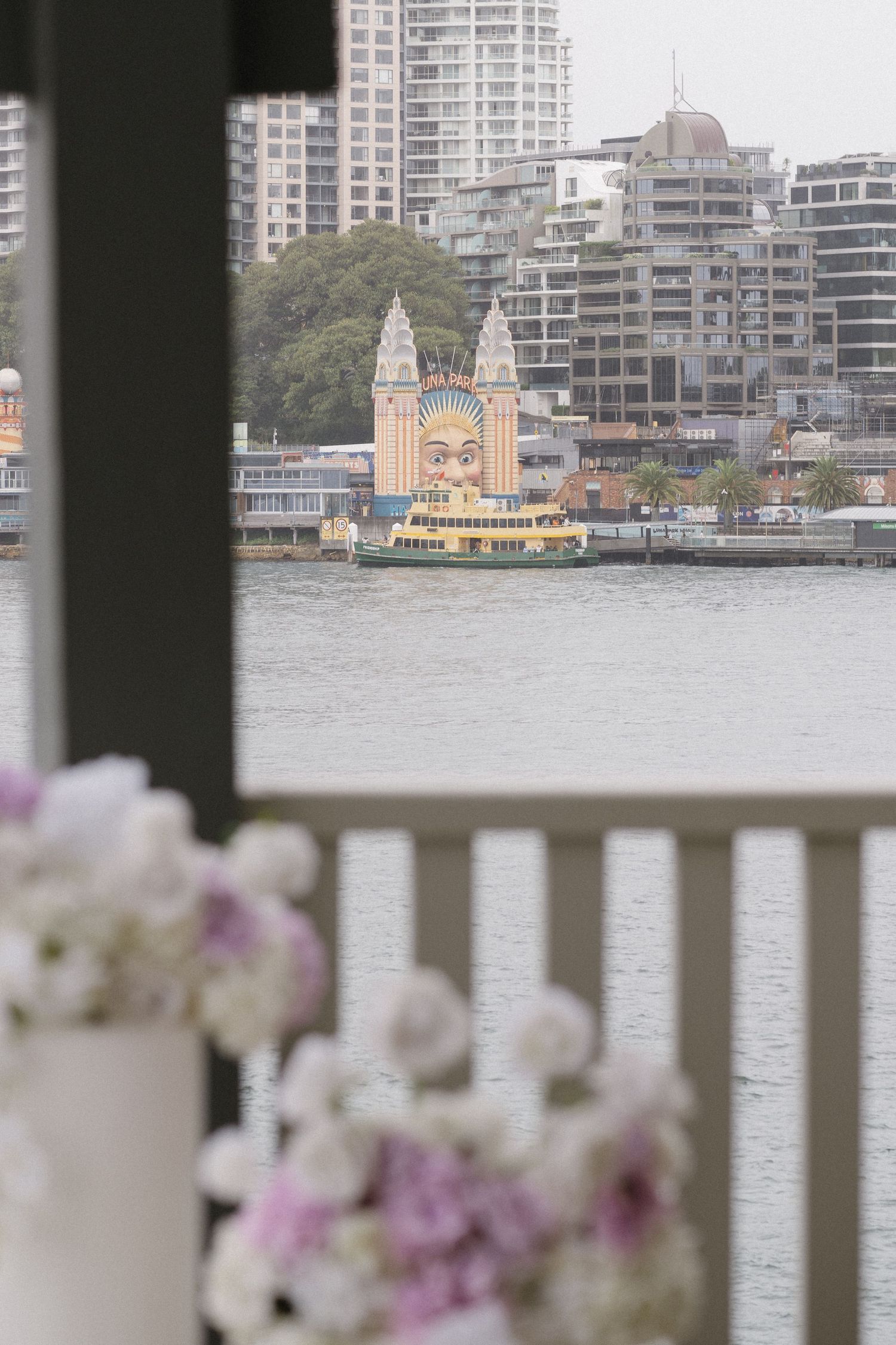 View of a waterfront church with white and purple flowers in the foreground.