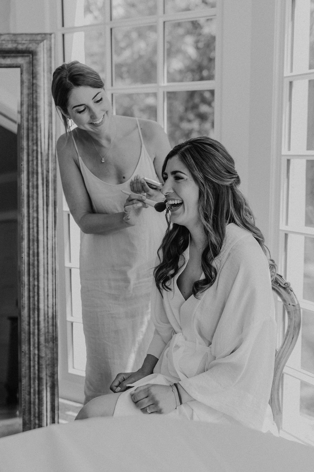 Getting Ready einer Hochzeit im Hofgut Heidesheim, die Braut trägt einen weißen Morgenmantel und lächt, Stylistin Anna Steiner.