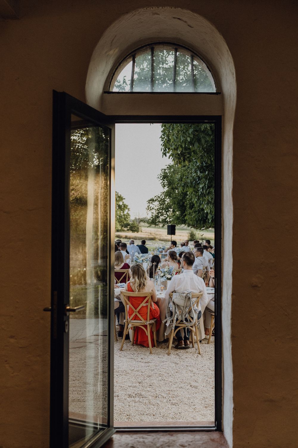 Blick durch eine Tür auf die Hochzeitsgesellschaft, die das Dinner unter freiem Himmel im Hofgut Heidesheim einnimmt.