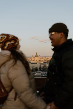 Two people viewing the cityscape of Budapest at dusk with Saint Stephen's Basilica dome visible in the background.
