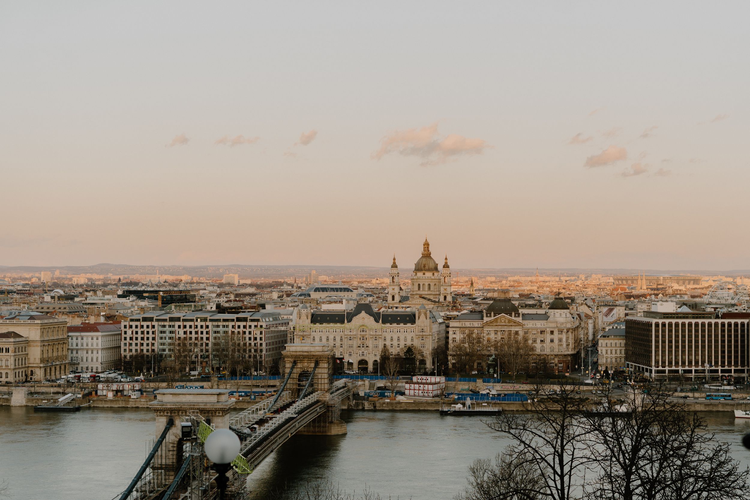 Aerial view of Budapest's cityscape at sunset with the iconic Parliament Building and Chain Bridge over the Danube River.