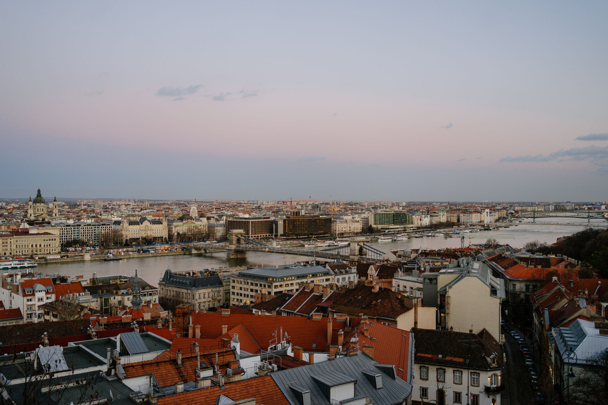 A scenic view over Budapest cityscape at dusk showcasing iconic bridges and historic architecture along the Danube River.