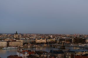 Panoramic sunset view of Budapest's historic cityscape along the Danube River with ornate architecture and buildings.