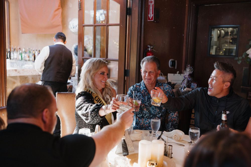 A group of people dining together at a restaurant table with drinks and ambient lighting.