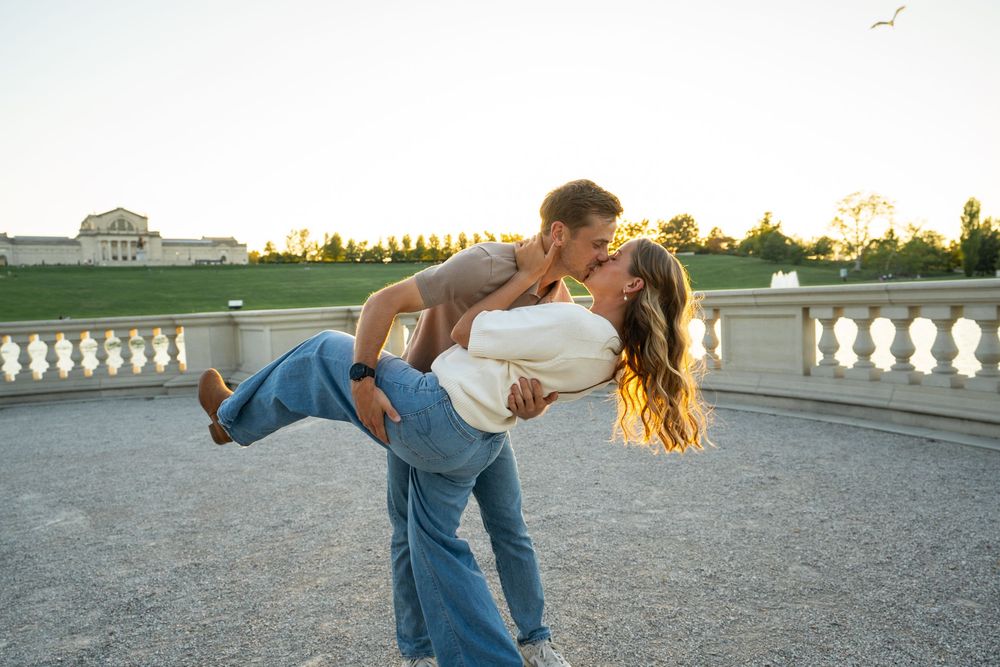 A couple dances together on a rooftop terrace at sunset with elegant white balustrades in the background.