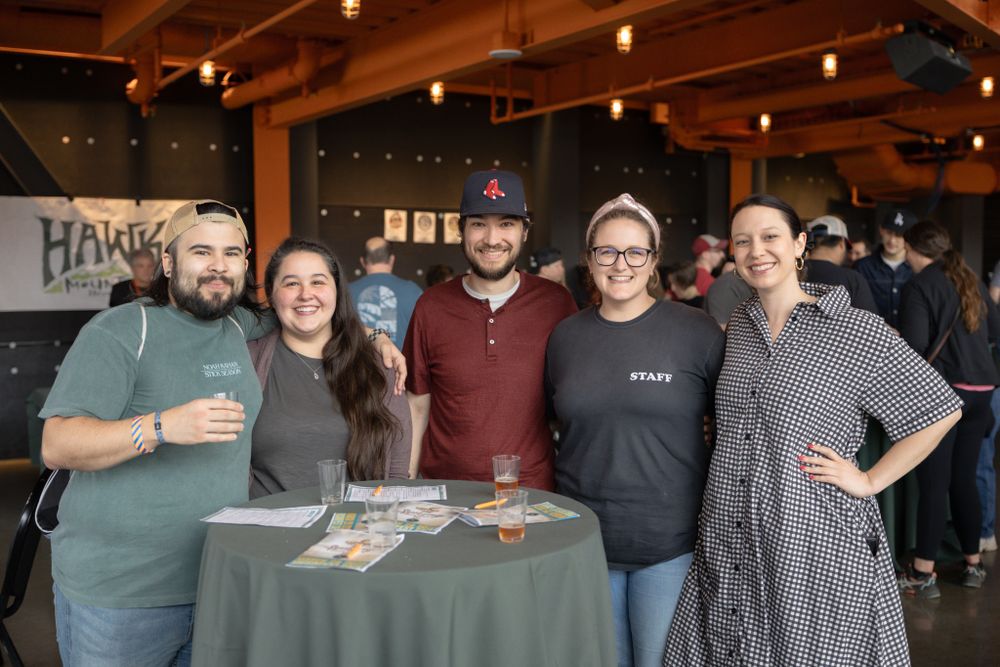 Friends gathering for drinks and photos at an industrial-style taproom event.