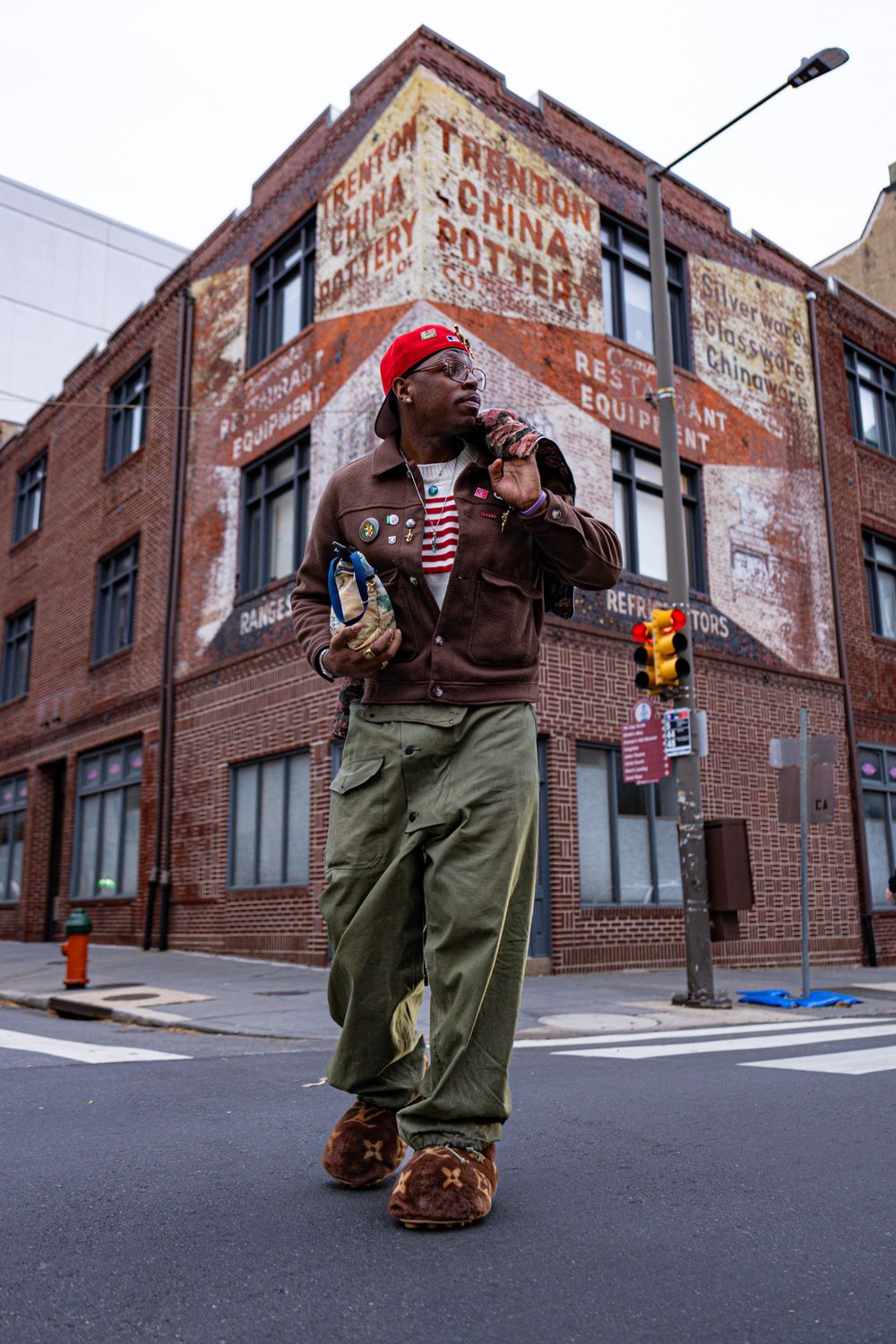 A sequence of photos showing someone in a red beanie and brown jacket walking past brick buildings on an urban street corner.