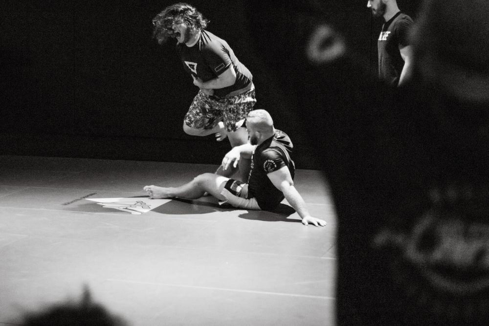Athletes engaged in intense wrestling match on competition mat.