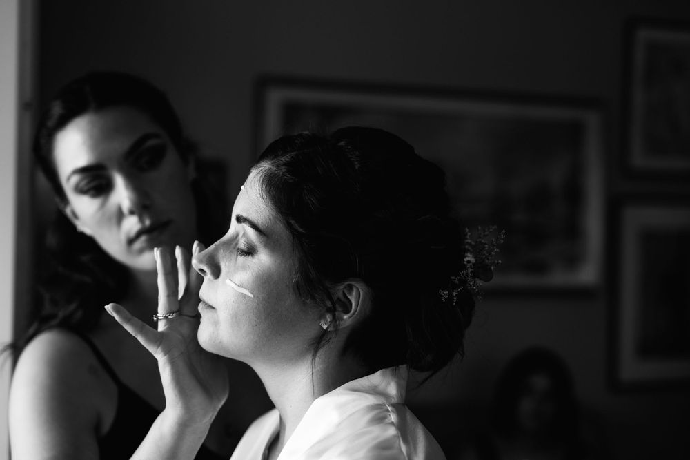 Black and white image of makeup application during formal event preparation.