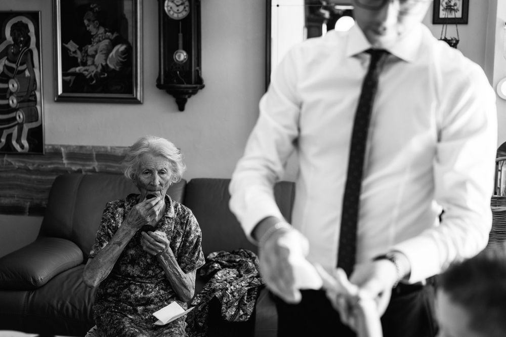 Monochrome photo of a home interior with someone in a tie and an elderly person seated on a couch.