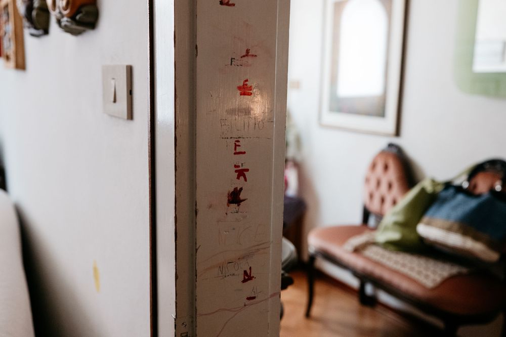 Height measurements and markings on a wall near a window and couch.