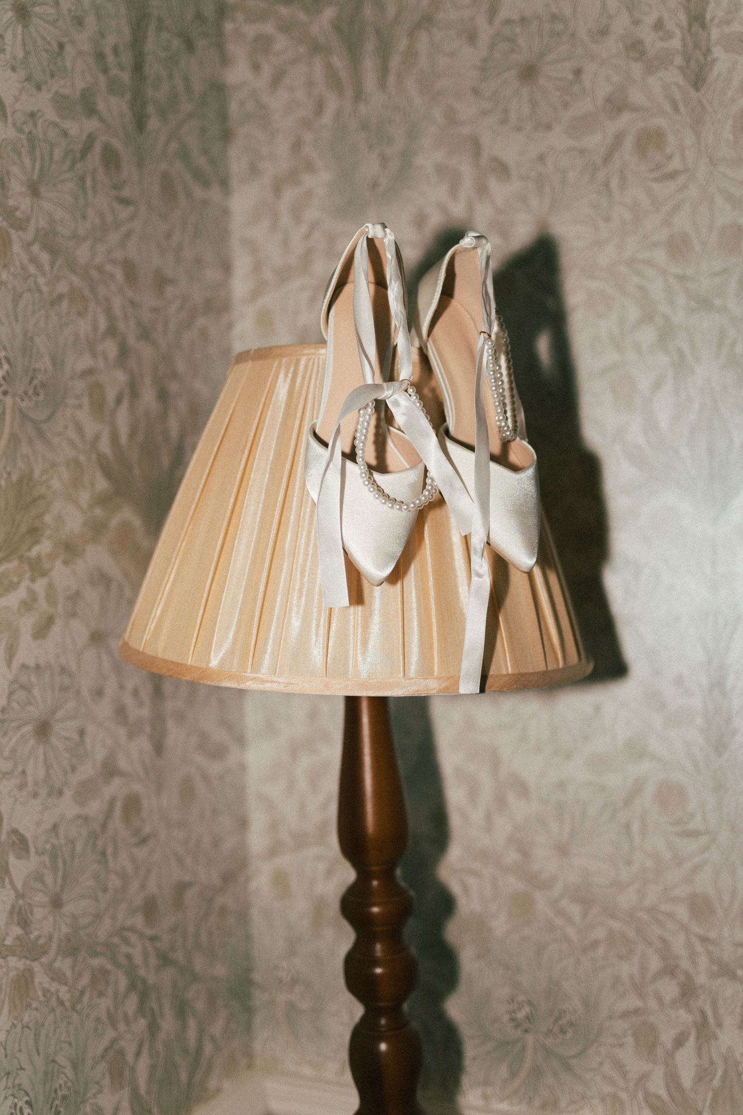 Vintage table lamp with pleated shade against floral wallpaper.