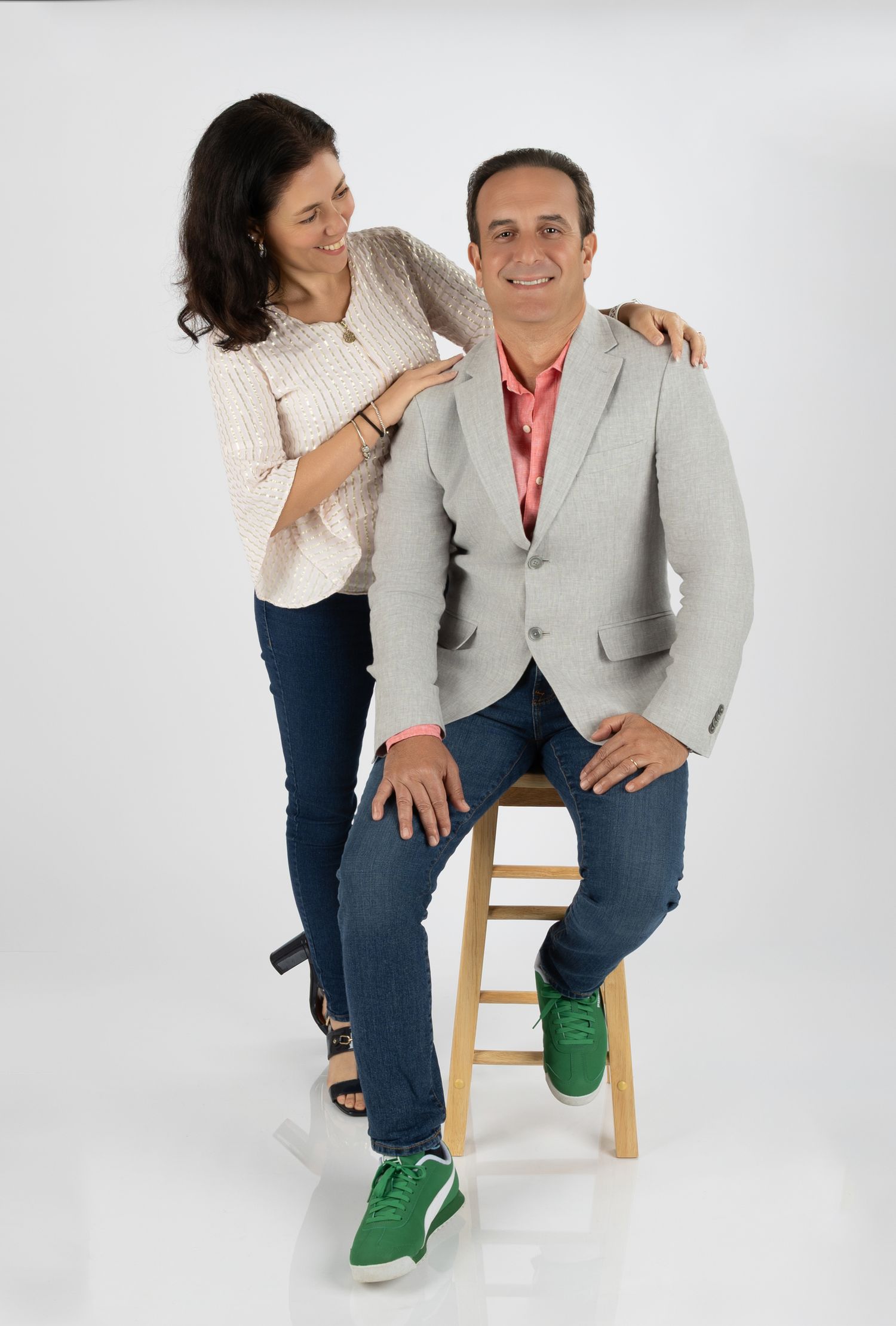 Professional studio portrait of couple posing casually against white background.
