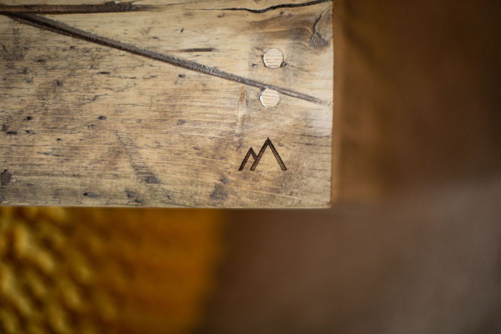 Close-up detail of a rustic wooden surface with a carved letter M and other markings.