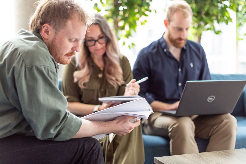 Team members collaborating over documents and laptop in modern office space.