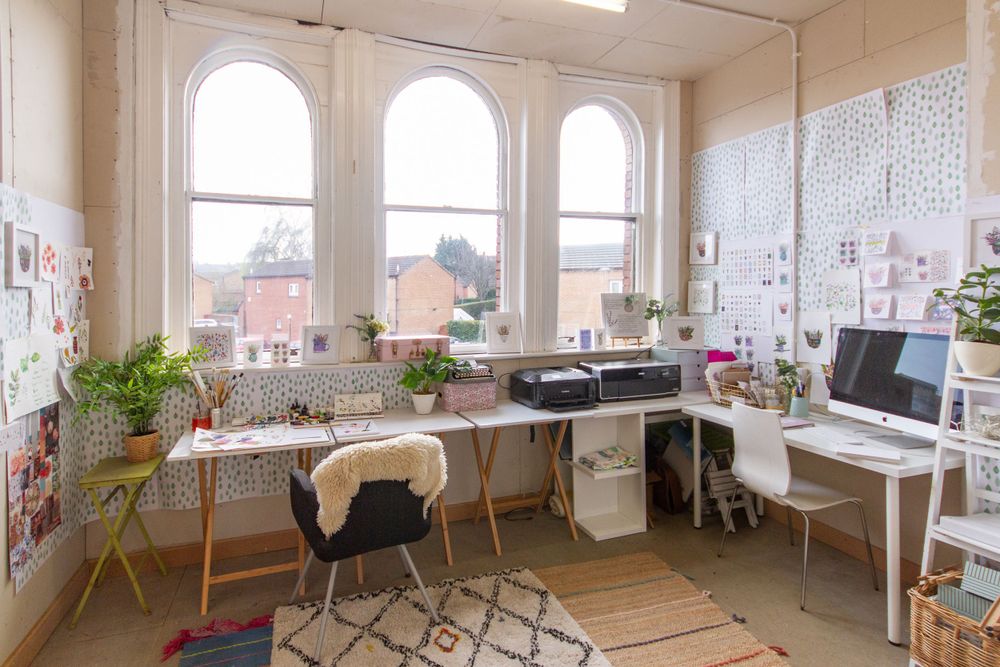 Bright home office with arched windows, white walls, and creative workspace setup.