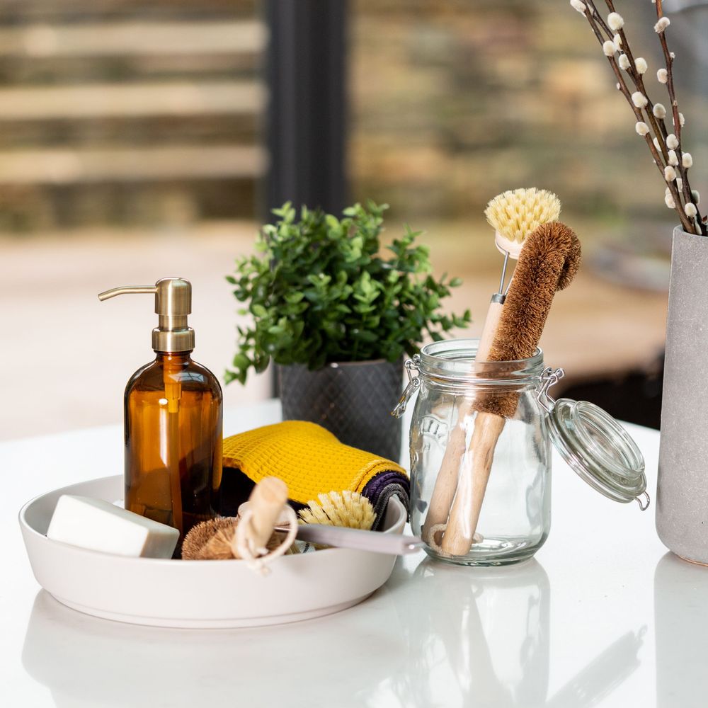 Minimalist bathroom tray with amber bottle, natural sponge, and dried flowers.