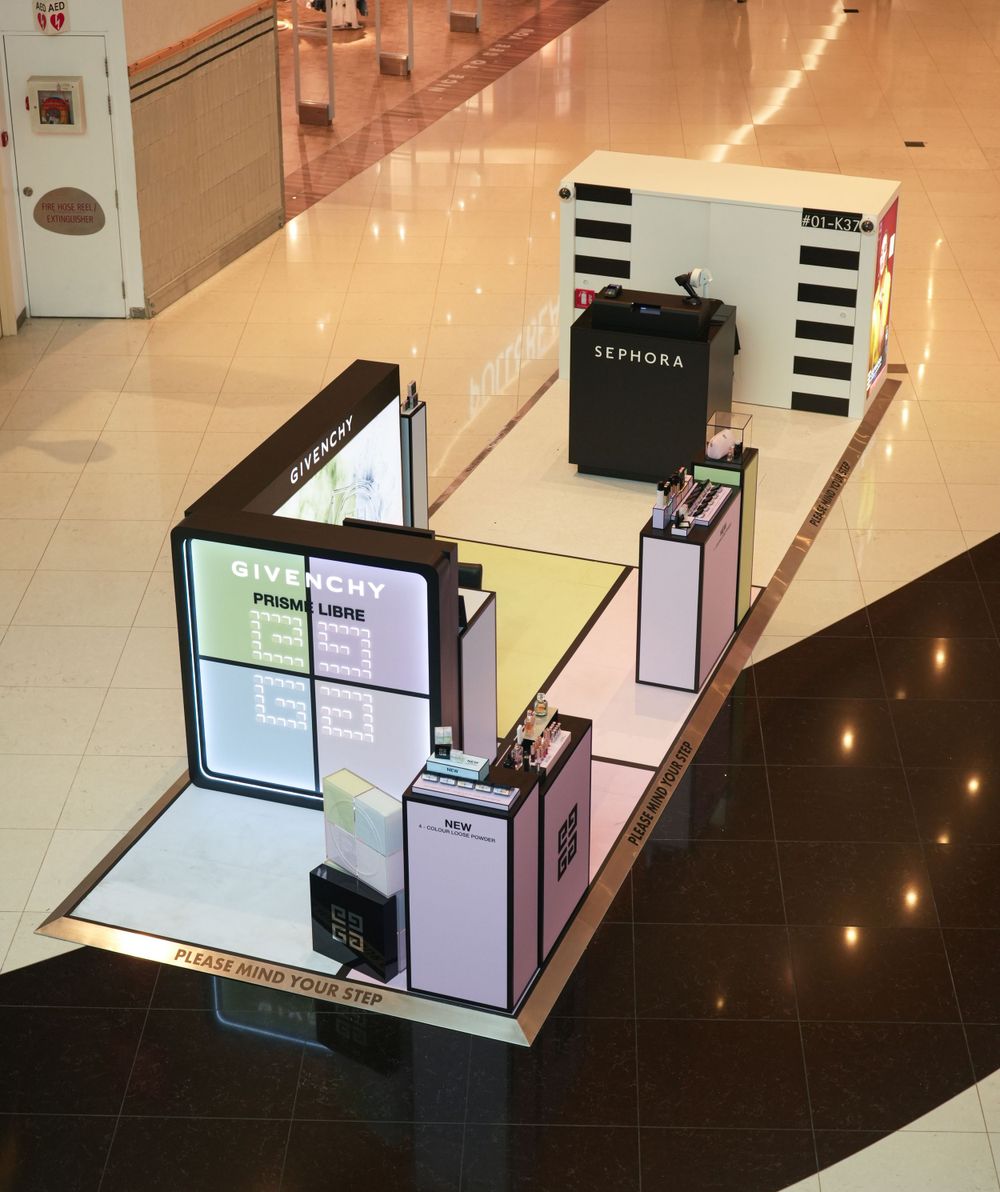 Minimalist retail display with black and white elements and digital screens in a shopping center.
