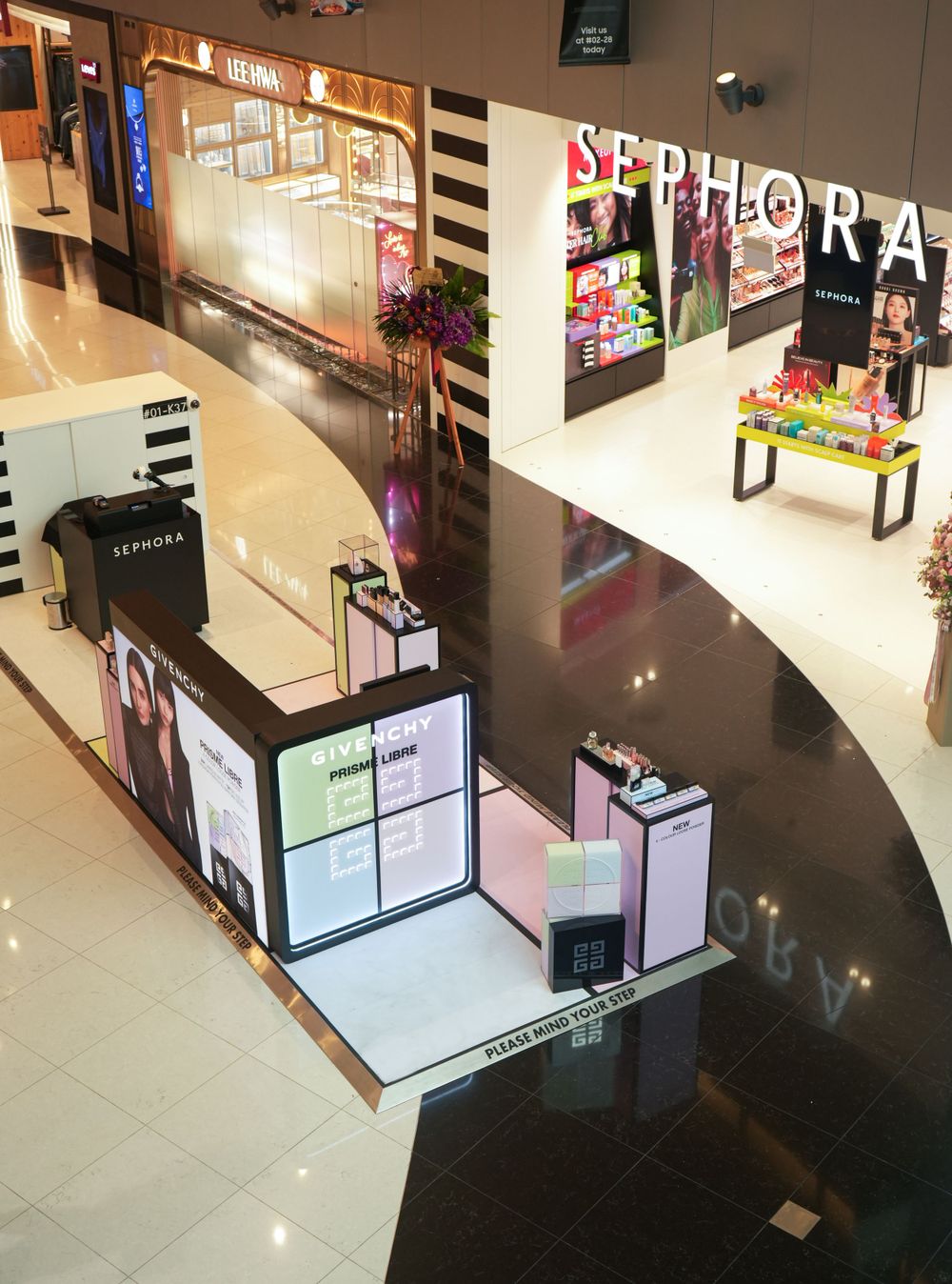 Modern retail kiosk with digital displays and striped design elements in a shopping mall interior.